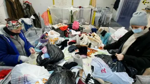 Two women working in clothing collection warehouse