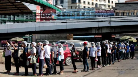 AFP People queue to be tested for Covid-19 at a seafood market in Samut Sakhon on December 19, 2020