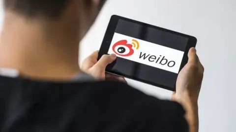 Getty Images A man uses the Sino Weibo social media platform on a mobile device