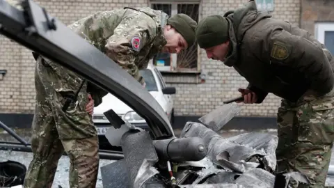 Reuters Soldiers examine the remains of a missile near Kyiv