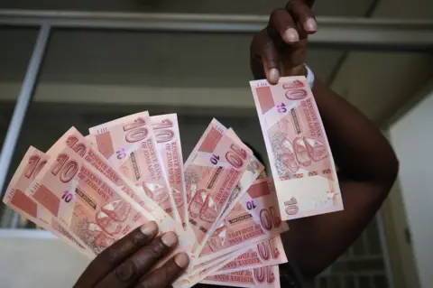 EPA A woman holds several newly introduced bank notes, all in denominations of 10.