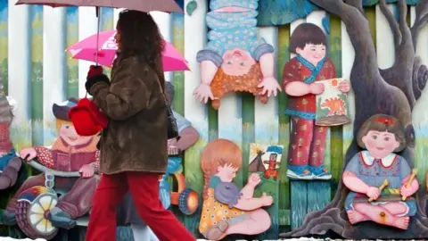 Toronto Star via Getty Images People are seen walking by the smiling faces and idyllic scenes of the Network Childcare Services