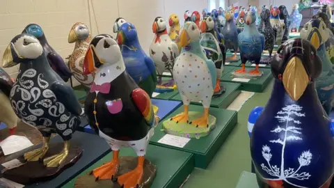 GSPCA Decorated puffin statues in rows indoors
