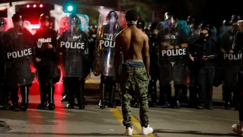 Reuters A protester faces off with law enforcement officials after Jason Stockley's acquittal (15 September 2017)