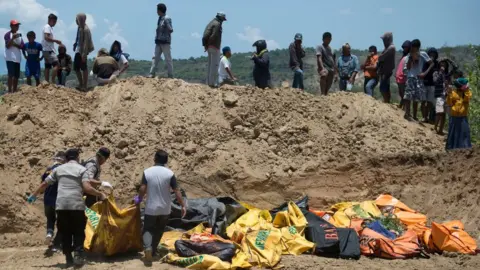 AFP/Getty Images People carry body bags into a mass grave in Palu, Indonesia. Photo: 1 October 2018