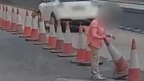 She is seen getting out of her car in traffic before trying to cut through to the other carriageway.