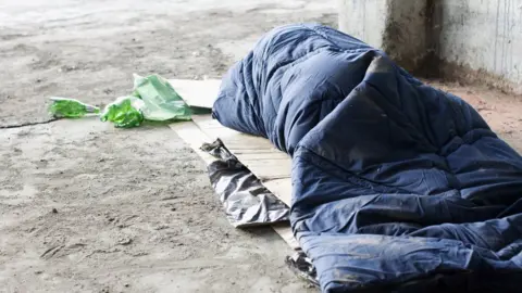 Getty Images A homeless man sleeping on cardboard