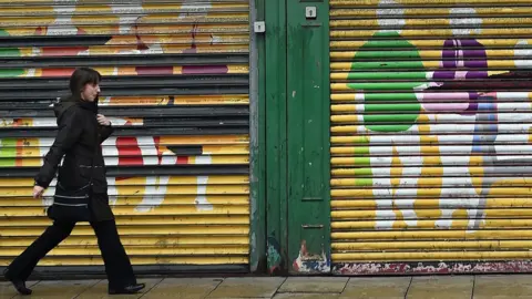 Getty Images A woman walks past shop shutters in Sunderland