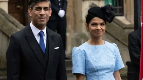 Getty Images Rishi Sunak and his wife Akshata Murty arrive at Westminster Abbey.