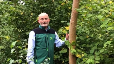 Steve Scott Steve Scott of Forestry Commission standing next to an ash tree