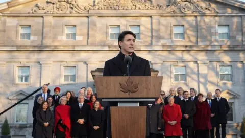 AFP Prime Minister Justin Trudeau at a podium with his new cabinet standing behind him