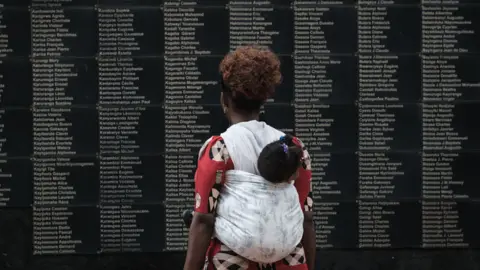 AFP A woman carrying her child looks at the wall of victims' names as Rwanda marks the 25th anniversary of the 1994 Genocide at the Kigali Genocide Memorial in Kigali, Rwanda - 8 April 2019