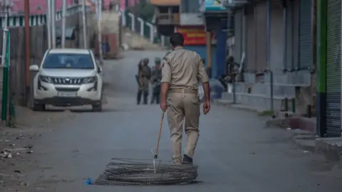 Abid Bhat A security officer drags a coil of barbed wire behind him