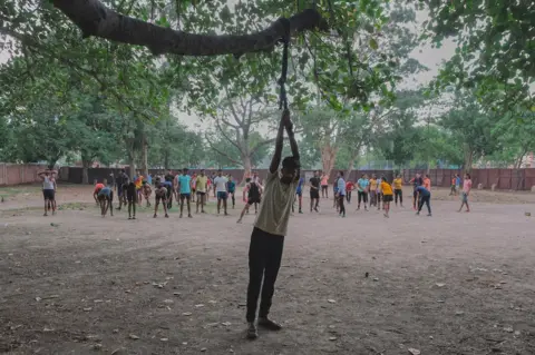 Ronny Sen Under a large banyan tree young men train for physical tests for the defence exams