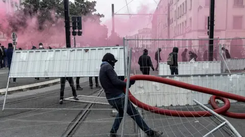 AFP Protesters dressed in black build a barricade amid tear gas smoke during a demonstration to protest against the pension overhauls, in Nantes, on December 5, 2019,