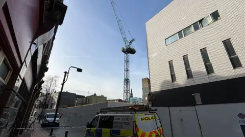 BBC/WILL ROSE Police cordon with crane in background
