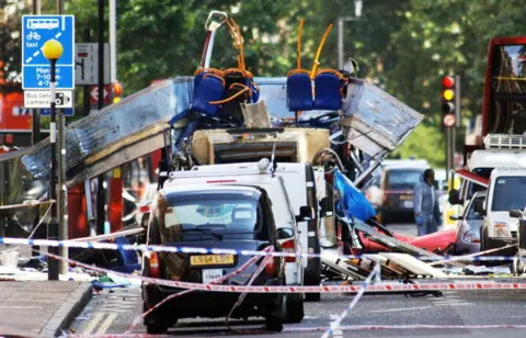 Fiona Hanson/PA A bus with its roof blown off is on a road.