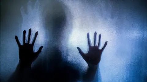 Getty Images Hands pressed against opaque glass