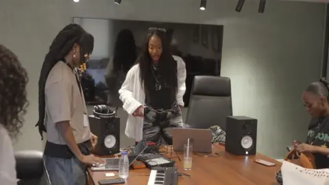 Nigerian Afropop star says 'women are not respected in the industry' Tems looks at a young woman, who is using a laptop connected to various musical equipement