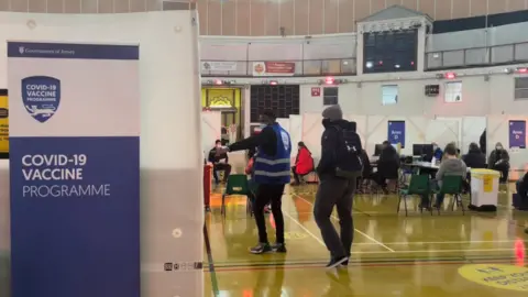 BBC Man directing person to desk for vaccination