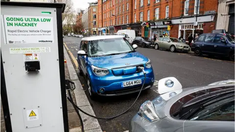 Getty Images A Nissan Leaf and a Kia Soul charge on a street in Hackney, London.