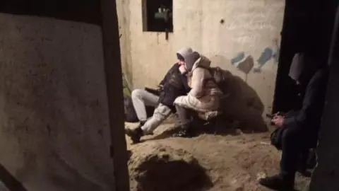 Amaliia Filatova People huddling in an basement