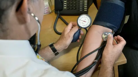 Anthony Devlin/PA Media File photo of a GP checking a patient's blood pressure