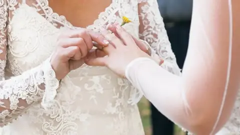 A ring is being placed on someone's finger at a wedding ceremony.