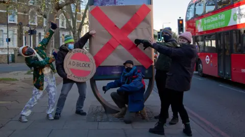 Camille Aboudaram Campaigners from Adblock Lambeth covering over an outdoor advert