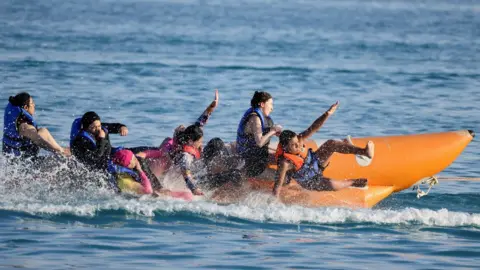 Amr Abdallah Dalsh/Reuters People riding on a banana boat on 23 July 2023