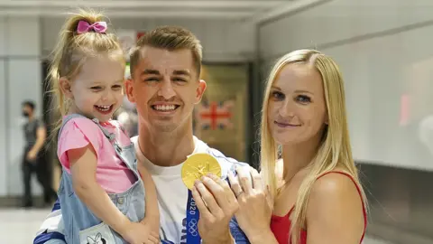 PA Media Max Whitlock with his wife and daughter at London Heathrow