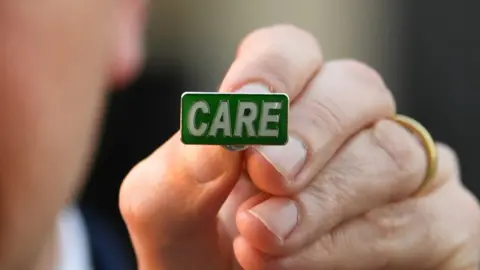 PA Media Matt Hancock with a CARE badge