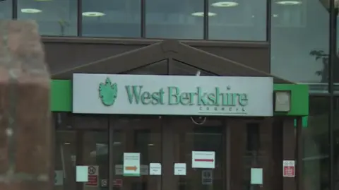 BBC The exterior of West Berkshire Council Offices, including a large glass facade and a silver sign with the council's name in green letters.