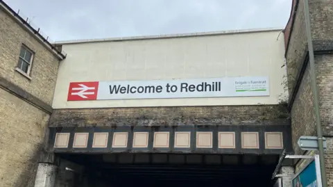 Local Democracy Reporting Service A grimy brick façade with a sign saying 'welcome to Redhill'