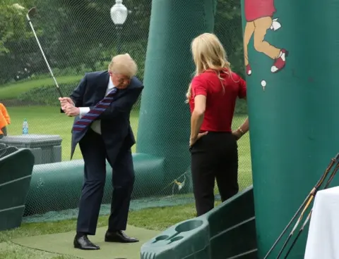 Reuters Mr Trump swung a golf club during the event on the White House lawn