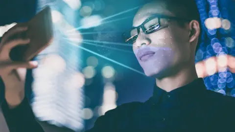 Getty Images Man with mobile phone and face being scanned