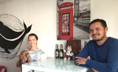 Nikolai and his wife in their flat with London poster