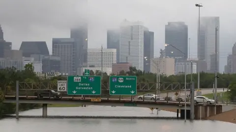 AFP/Getty The city is pictured beneath clouds as a whole highway is overwhelmed by flood waters almost reaching the over-road signage