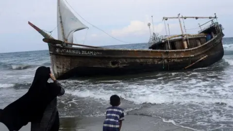 Reuters Residents of Indonesia's Aceh province look at the boat that carried the Rohingya refugees. Photo: 25 December 2022