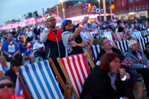 Reuters People watch a screening of the concert marking Britain's King Charles' coronation, on Blackpool Promenade, in Blackpool, Britain May 7, 2023