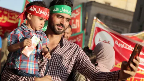 Amr Abdallah Dalsh/Reuters A man and his son with headbands in Arabic reading: "Prophet my love" in Cairo, Egypt - Wednesday 27 September 2023