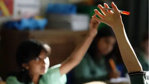 Getty Images Pupils raise hands in class