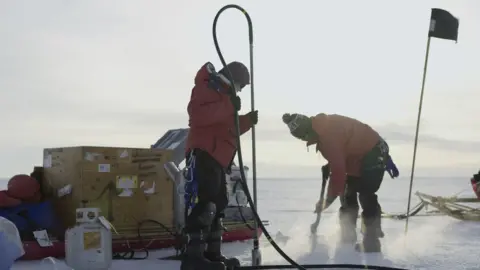 BBC Studios Scientists from the Thwaites Glacier Collaboration (ITGC) use a hot water drill to make a tiny hole through the ice shelf in order to sink a probe which will monitor the water beneath.