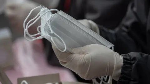 European Photopress Agency person wearing surgical gloves holding surgical masks.