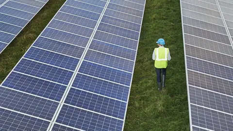 Mike Harrington Man walking past solar panels