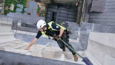 PA Media Lewis Head analyses the stone on the West Towers