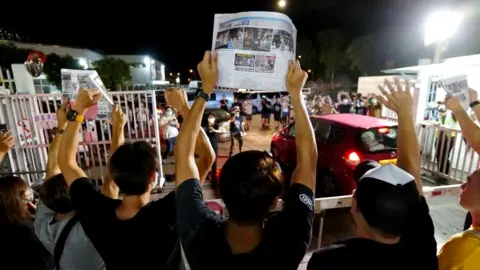 Getty Images Apple Daily journalists hold freshly-printed copies of the newspaper's last edition while acknowledging supporters gathered outside their office in Hong Kong