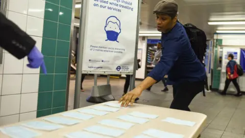 Getty Images Man picking face coverings from table