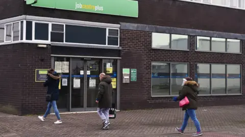 Getty Images People walk past a Job Centre office