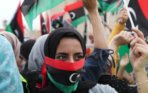 Reuters A Libyan woman covers her face with Libyan flag as she attends a demonstration to demand an end to the Khalifa Haftar"s offensive against Tripoli, in Martyrs" Square in central Tripoli, Libya April 26, 2019